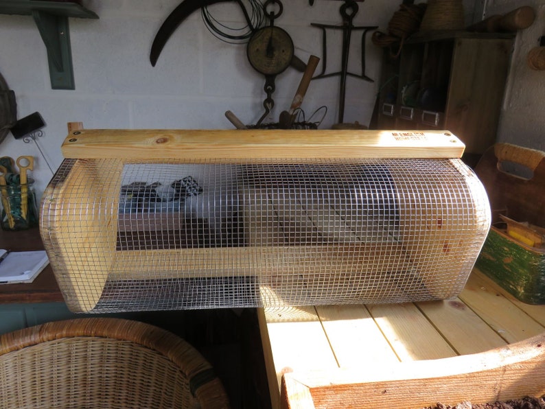 May include: A wooden and wire cage with a curved top and a wooden base. The cage is made of natural wood and has a wire mesh on the front and sides.