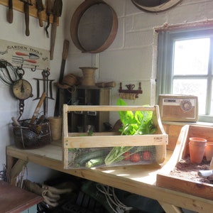 May include: A wooden crate with a wire mesh insert, filled with fresh produce, including lettuce, zucchini, and tomatoes. The crate is sitting on a wooden workbench in a garden shed. There is a vintage radio and gardening tools on the wall.