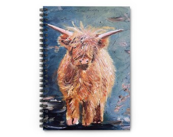 May include: A spiral bound notebook with a painting of a fluffy, light brown Highland cow standing on a blue and gray background.
