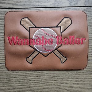 May include: Brown leather patch with a baseball, two crossed bats, and the text "Wannabe Baller" in red embroidery.