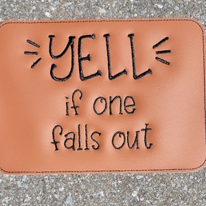 May include: A brown leather doormat with black embroidered text that reads "YELL if one falls out".