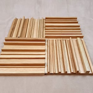 May include: A set of four wooden acoustic panels, each with a different pattern of vertical slats. The panels are made of light brown wood and are arranged in a square.