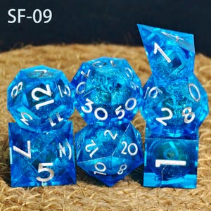 May include: A collection of six blue resin dice with silver numerals. The dice are in different shapes, including a cube, a 12-sided die, and a 20-sided die. The text "SF-09" is visible in the top left corner.