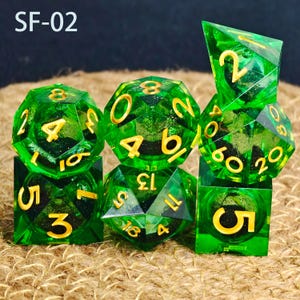 May include: A set of seven green polyhedral dice with gold numbering. The dice are various shapes, including a d4, d6, d8, d10, d12, d20, and a cube. The text "SF-02" is in the upper left corner.