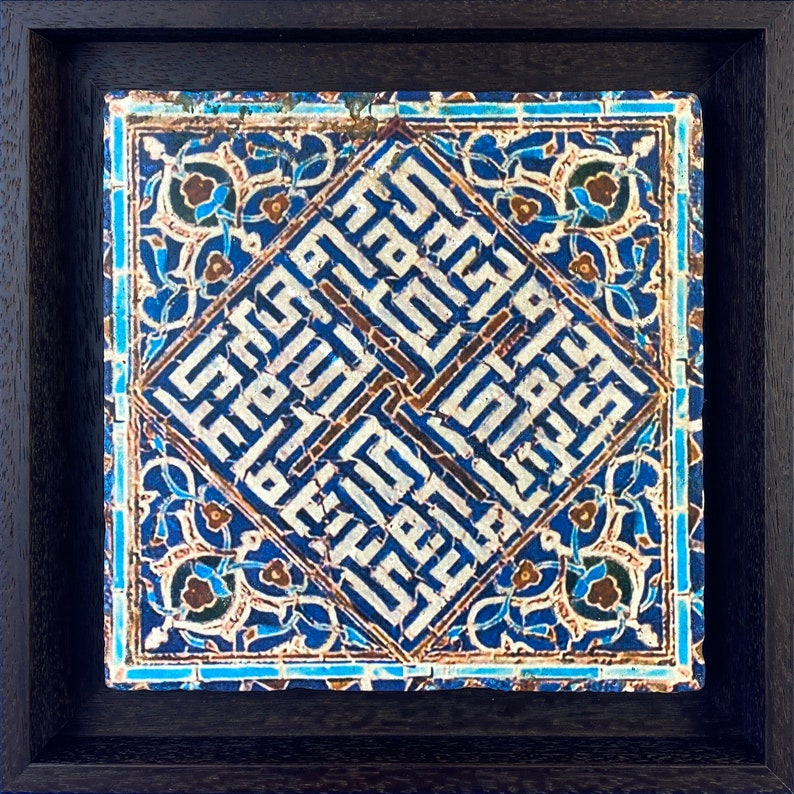 Peut inclure: Un carreau de c&eacute;ramique encadr&eacute; avec un motif g&eacute;om&eacute;trique bleu et blanc. Le carreau pr&eacute;sente une calligraphie arabe complexe en forme de losange, entour&eacute;e de motifs floraux.