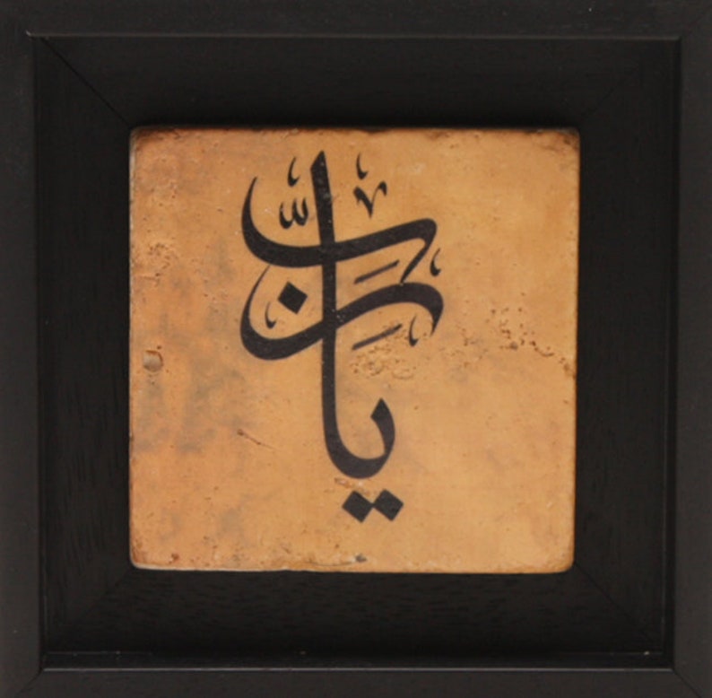 May include: A framed tile with black calligraphy on a tan background. The calligraphy is in Arabic script and reads "Allah".