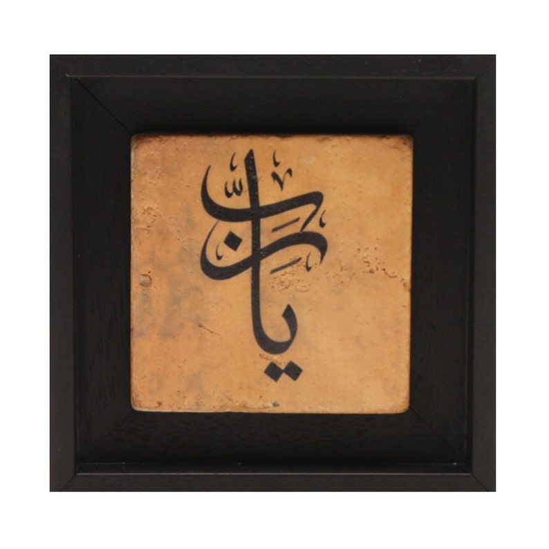 May include: A framed piece of art featuring black calligraphy on a tan background. The calligraphy is in Arabic script.