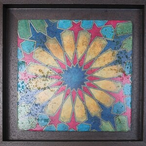 May include: A framed tile with a geometric pattern in shades of blue, yellow, red, and green. The pattern is made up of stars and other shapes.