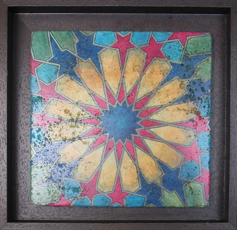 May include: A framed tile with a geometric pattern in shades of blue, yellow, red, and green. The pattern is made up of stars and other shapes.