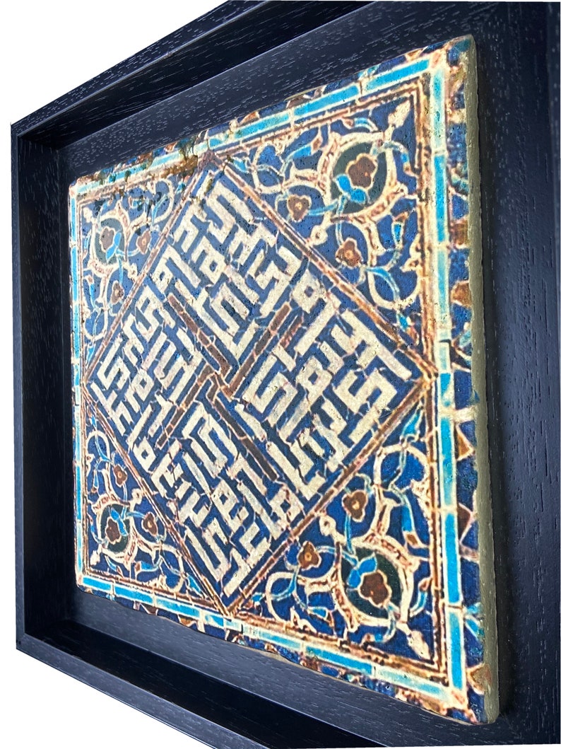 Peut inclure: Un carreau encadr&eacute; avec des motifs g&eacute;om&eacute;triques bleus et blancs complexes et de la calligraphie arabe. Le carreau est sur un fond bleu fonc&eacute;.