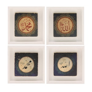 May include: Four framed square tiles with black and blue backgrounds. Each tile features a white circle with a gold border and Arabic calligraphy in black and red. The tiles are arranged in a 2x2 grid.