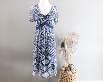 May include: A blue and white patterned midi dress with a V-neck and short sleeves. The dress has a geometric design and is made of a lightweight fabric.