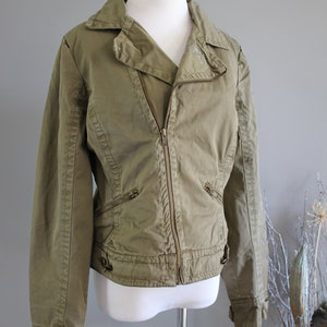 May include: A green cotton jacket with a zipper closure and multiple pockets. The jacket has a slightly fitted silhouette and a collar.