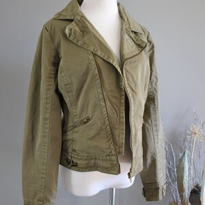 May include: A green zippered jacket with a collar and long sleeves. The jacket has a zipper closure and multiple pockets.