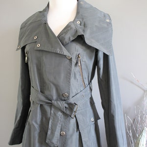 May include: A gray plaid trench coat with a large collar, a belt, and multiple pockets.