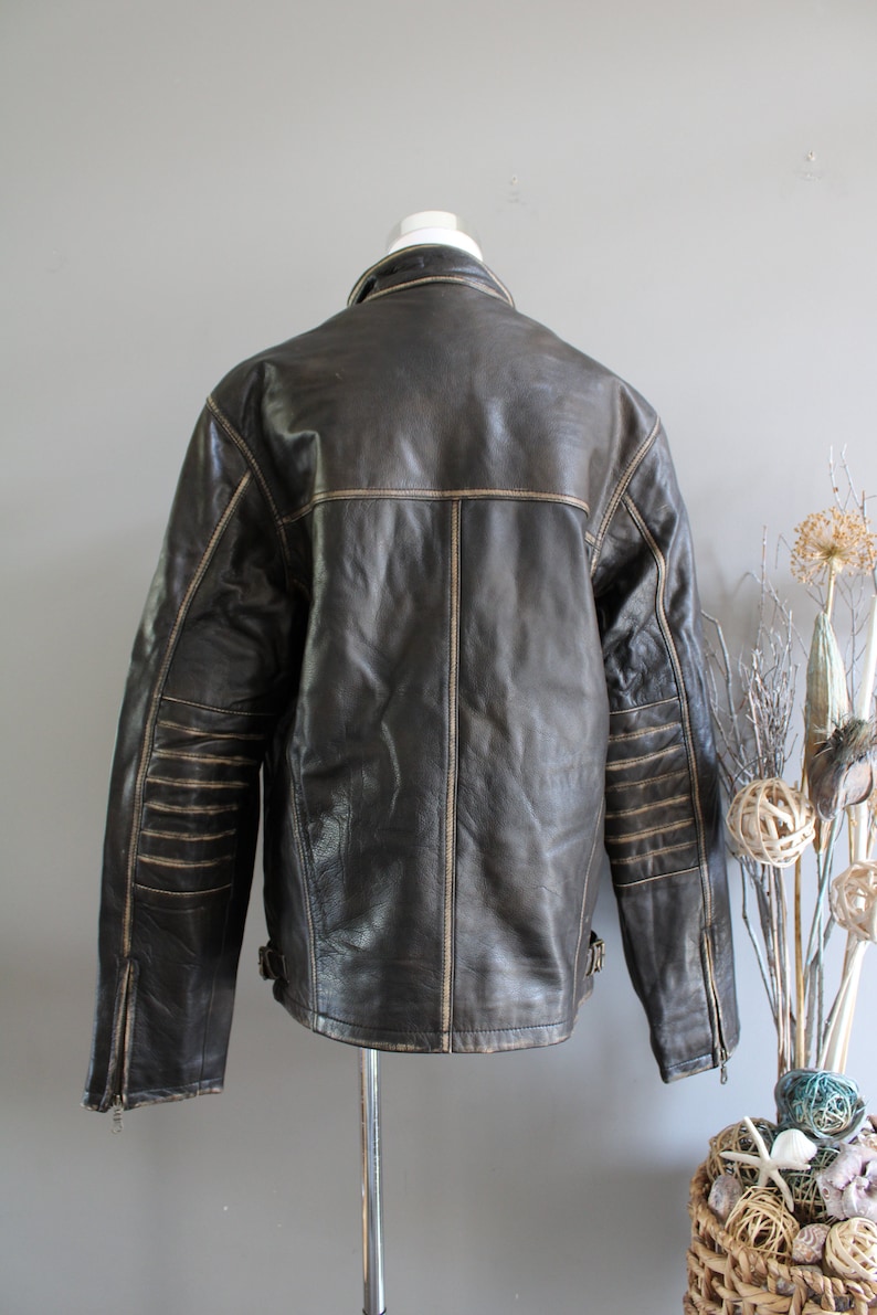 K&ouml;nnte beinhalten: Eine braune Lederjacke mit Rei&szlig;verschluss und Stehkragen. Die Jacke hat einen Used-Look mit hellbraunen N&auml;hten und einem Rei&szlig;verschluss an jedem &Auml;rmel.