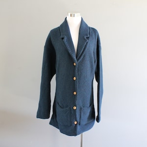May include: A dark blue knitted cardigan with a collar, button closure, and two pockets.