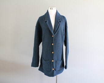 May include: A dark blue knitted cardigan with a collar, button closure, and two pockets.