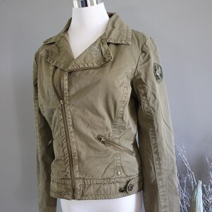 May include: A green, zippered, moto-style jacket with a decorative patch on the sleeve.