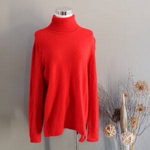 May include: A bright red turtleneck sweater with long sleeves. The sweater is made of a soft, knitted fabric.