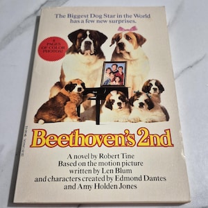 May include: A book cover for "Beethoven's 2nd" featuring Saint Bernard dogs and a family photo. The title is in yellow and red, with text stating "The Biggest Dog Star in the World has a few new surprises."