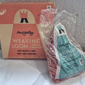 May include: A vintage "Majesty" weaving loom set with a box and a bag of jersey loops. The box is peach-colored with a crown logo and text. The bag is clear with a teal and white label.