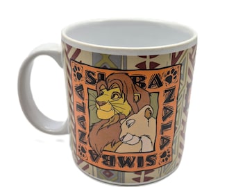 May include: White ceramic mug featuring Simba and Nala from The Lion King. The mug has a rectangular design with the words "Simba" and "Zala" around the image. The background has a geometric pattern in shades of brown, tan, and cream.