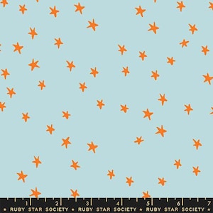 May include: Pale blue fabric featuring a random arrangement of orange stars. The stars are hand-drawn in style and spread across the material. The fabric is likely cotton or a similar material, ideal for sewing.