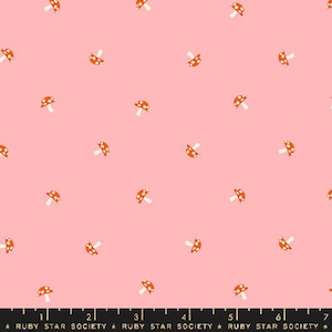May include: A pink fabric with a repeating pattern of orange mushrooms with white spots. The fabric has a ruler printed at the bottom with the text "Ruby Star Society".