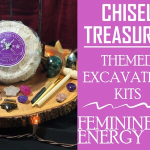 May include: A close-up of a themed excavation kit with a round block of plaster, a wooden chisel, a small brush, and various crystals. The kit is labeled "Chisel Treasures Themed Excavation Kits Feminine Energy".