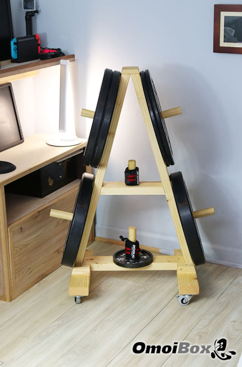 May include: A wooden weight plate stand with four weight plates and two pairs of wrist wraps. The stand has a triangular shape and is on wheels. The stand is made of light wood and has a natural finish.