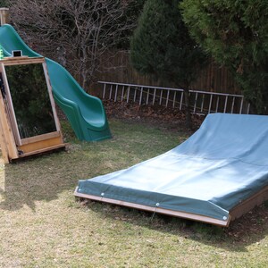 Puede incluir: Un tobog&aacute;n de pl&aacute;stico verde y un arenero de madera con una lona azul en un patio trasero.