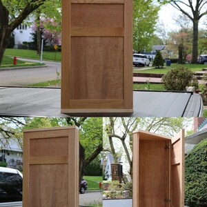 May include: A wooden cabinet with a hinged door. The cabinet is made of light brown wood and has a simple design. The door is open, revealing the empty interior of the cabinet.