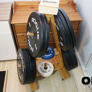 May include: A wooden weight plate stand with black weight plates that say "Rogue" on them. The stand has a small wooden box on top that says "Chalk".