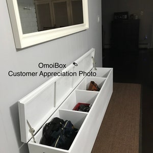 May include: White wooden storage bench with three compartments, two of which are open and show various items, including bags, shoes, and a purse. The bench is in a hallway with a mirror on the wall behind it.