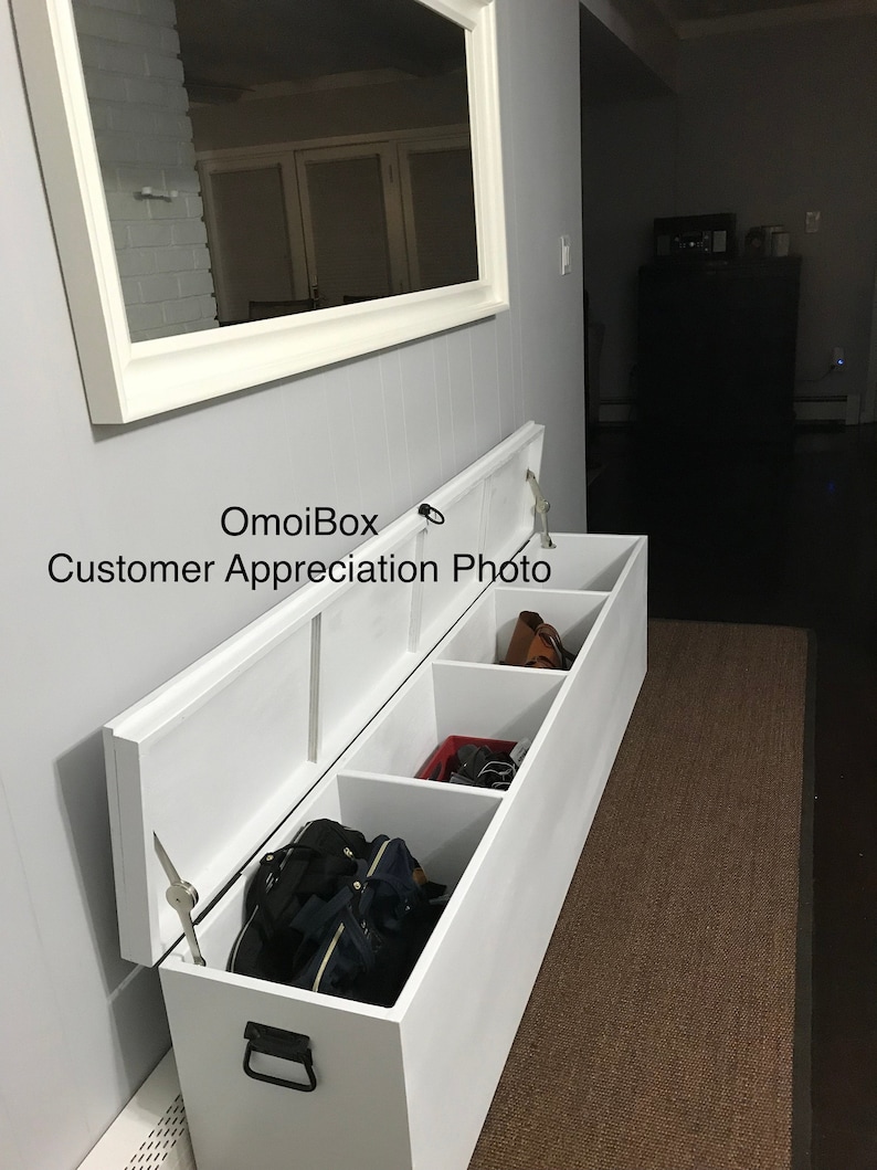 May include: White wooden storage bench with three compartments, two of which are open and show various items, including bags, shoes, and a purse. The bench is in a hallway with a mirror on the wall behind it.