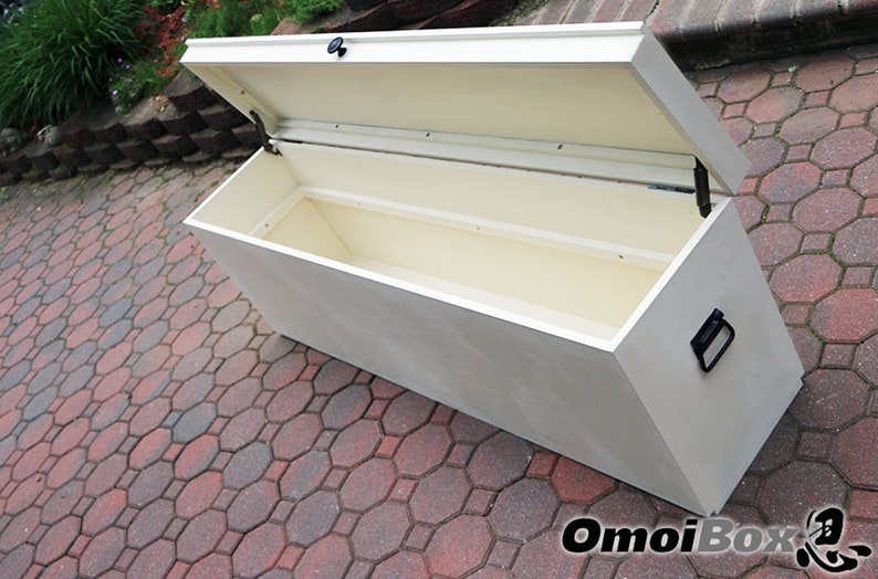 May include: White wooden storage bench with a hinged lid and a black handle. The lid is open, revealing the empty interior of the bench.