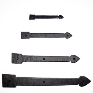 May include: Four black metal hinges of varying sizes. The hinges have a textured surface and a pointed tip.