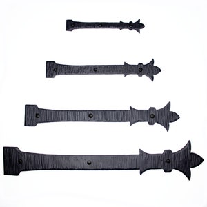 May include: Four black metal hinges with decorative fleur-de-lis finials. The hinges are of varying lengths.