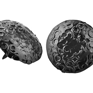 May include: Two black metal decorative nail heads with a circular design. The nail heads have a raised pattern of circles and swirls.