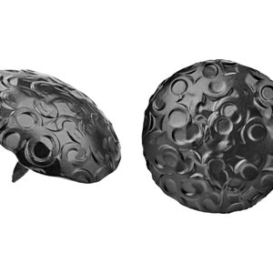 May include: Two black metal decorative nail heads with a circular, embossed design.