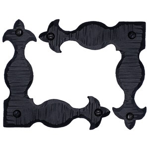 May include: Four black metal corner brackets with a decorative design. Each bracket has a rounded shape with a pointed top and a screw hole on the side.