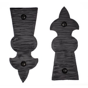 May include: Two black metal decorative door hinges with a pointed top and a rounded centre section. Each hinge has three visible screws.