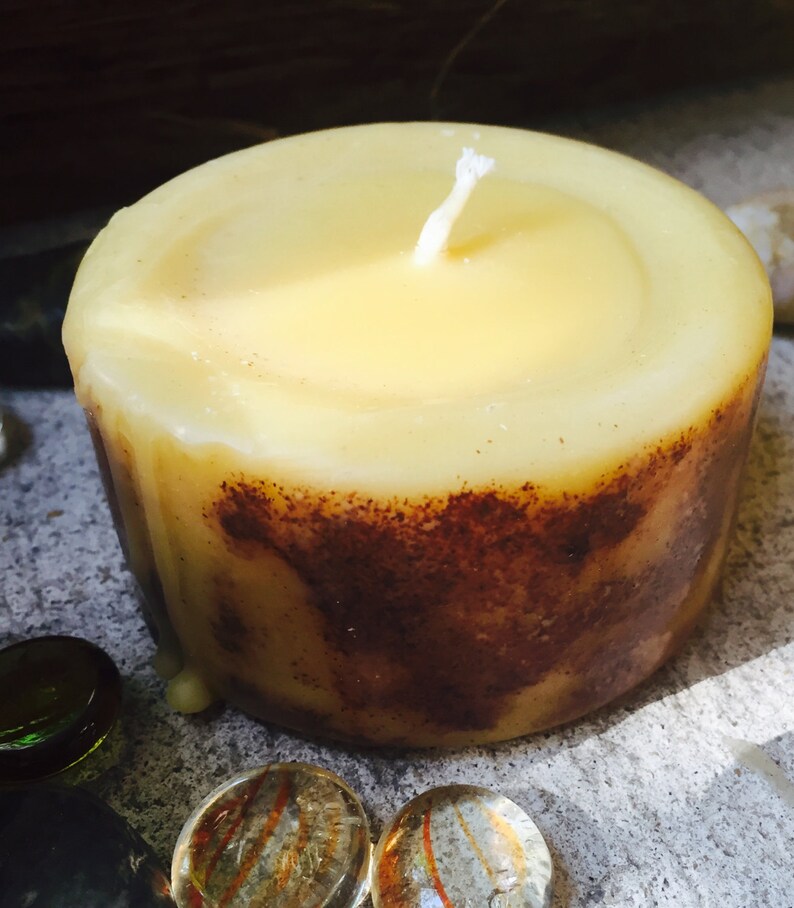 May include: A yellow beeswax candle with a white wick. The candle has a brown, textured base.