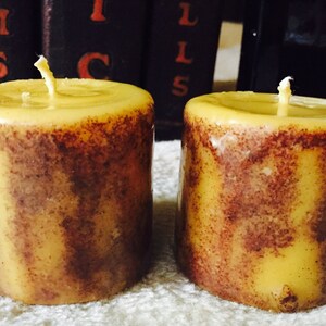 May include: Two yellow and brown striped pillar candles with wicks.