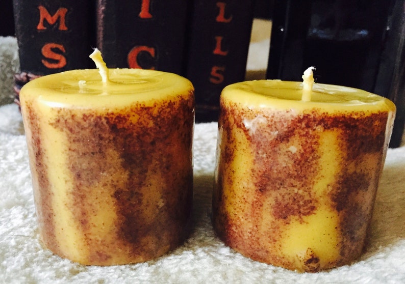 May include: Two yellow and brown striped pillar candles with wicks.