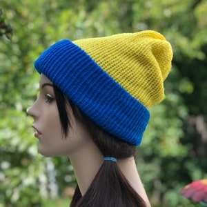 May include: A yellow and blue knitted beanie hat. The hat is made of soft yarn and has a simple design.