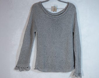 May include: A gray knitted sweater with a loose fit and long sleeves. The sweater has a delicate lace trim on the cuffs.