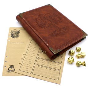 May include: A brown leather-bound journal featuring an embossed tree design on the cover with metallic corner accents, accompanied by two tan character sheets with printed text and illustrations, and a set of seven gold-colored polyhedral dice.