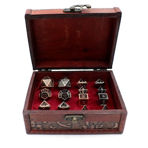 May include: A set of metal dice in a wooden box with a red velvet interior. The dice are in various shades of gold and silver, with black numbers.
